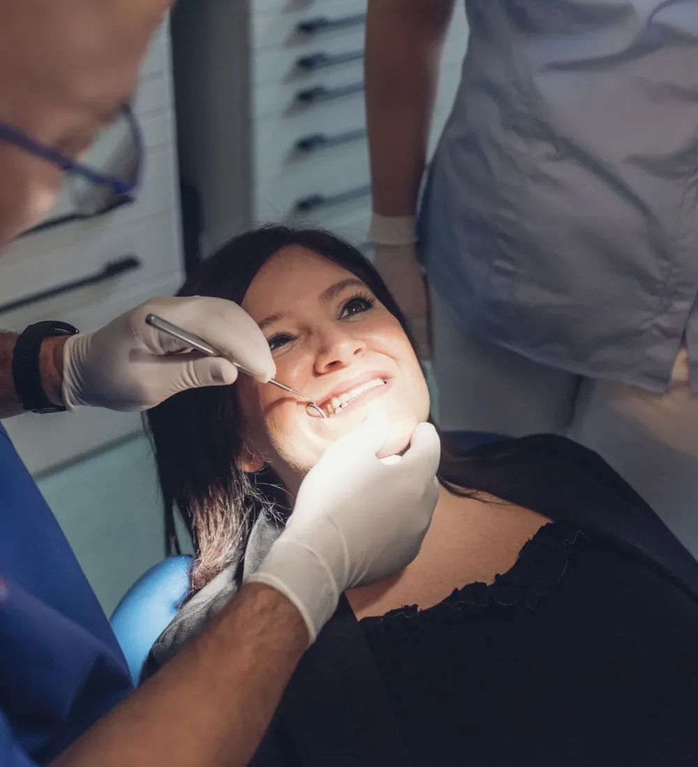 Dentist and dental nurse carrying out dental procedure on female patient